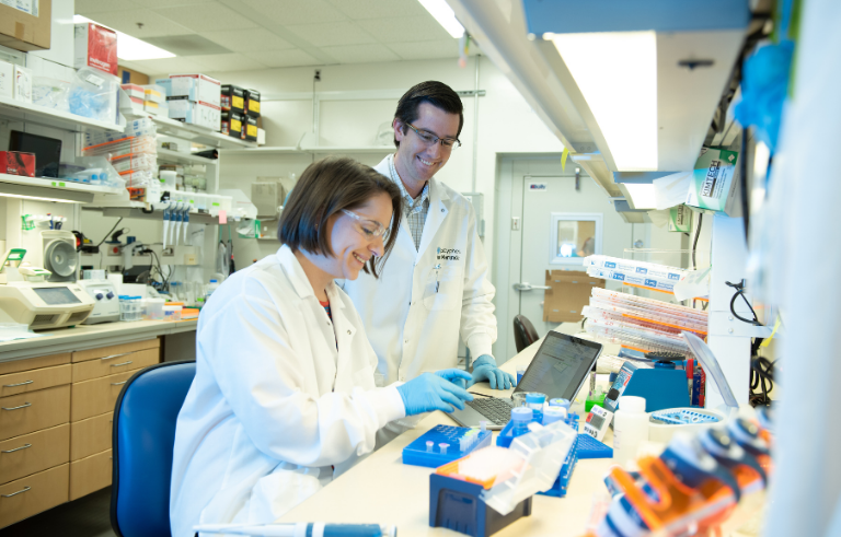 Two scientists studying drug resistance at a lab bench.